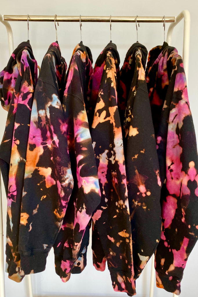 Black tie die hoodies with pink, white, and orange splatters