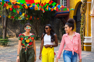 Three women walking in Mexico wearing colorful clothing with a colorful backdrop