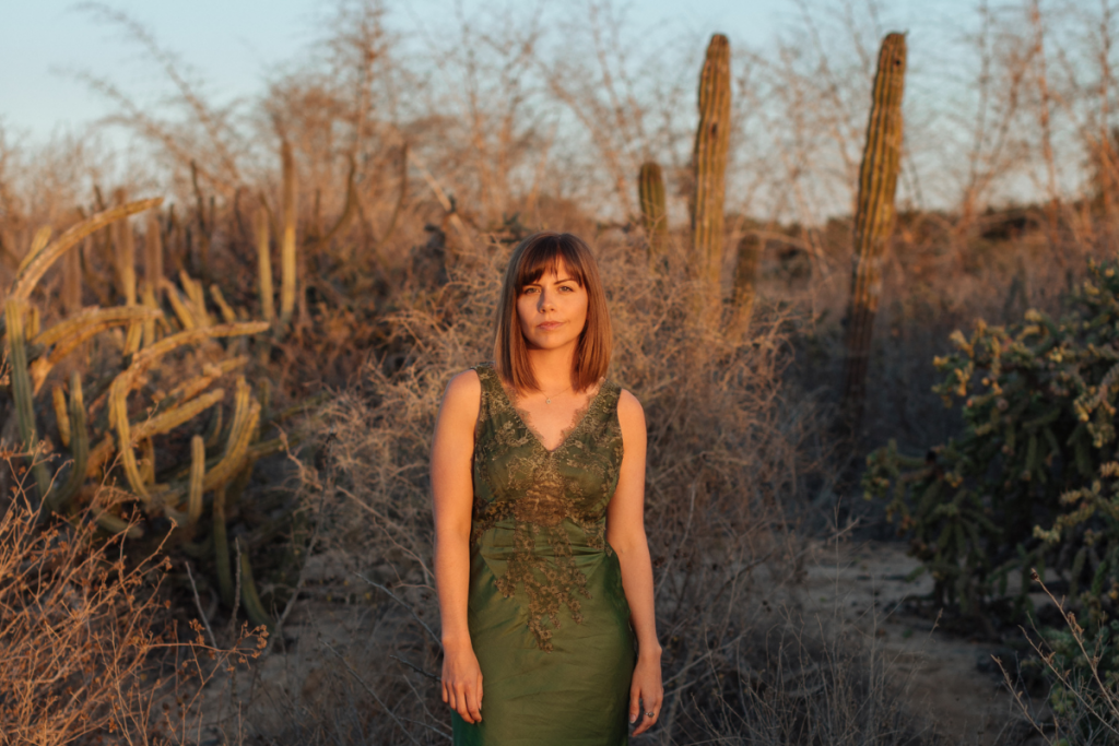 Wild Terrains founder Lauren Bates in Olive green dress in front of cacti